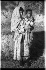 Young girl from Afghanistan carrying a small child from the Indian plains